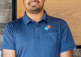 Raj Manchanda, CEO and founder of Domino’s Pizza Niagara Falls, standing inside his restaurant with pizza boxes and menu displays in the background.