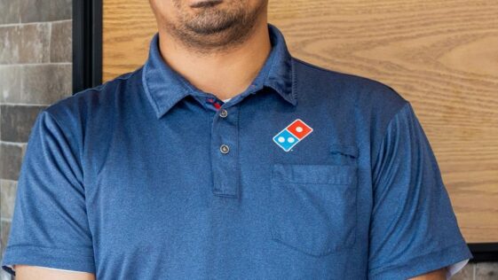 Raj Manchanda, CEO and founder of Domino’s Pizza Niagara Falls, standing inside his restaurant with pizza boxes and menu displays in the background.