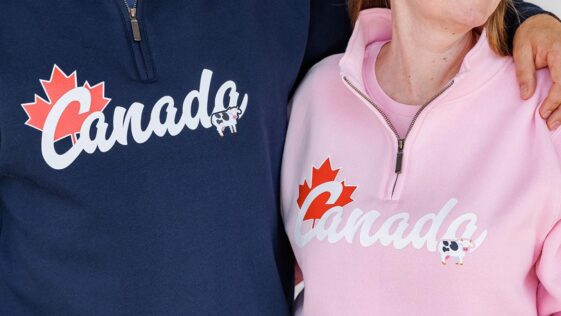 A smiling customer holding a waffle cone with COWS Ice Cream in front of the Niagara Falls store