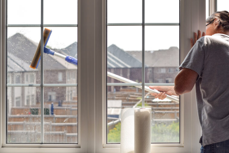 Tecahnician cleaning a large residential window in Niagara Falls – part of NLLC’s expert window cleaning services.