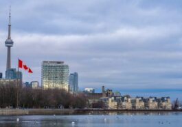 Canadian flag waving in front of the Toronto skyline and CN Tower, representing Ontario immigration news.