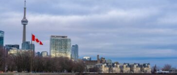 Canadian flag waving in front of the Toronto skyline and CN Tower, representing Ontario immigration news.