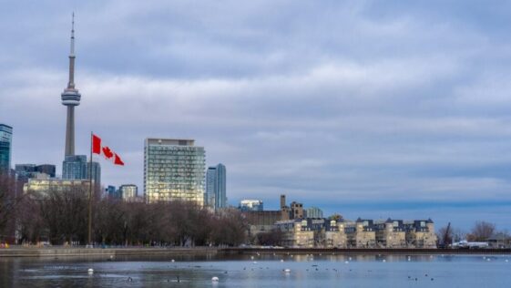 Canadian flag waving in front of the Toronto skyline and CN Tower, representing Ontario immigration news.